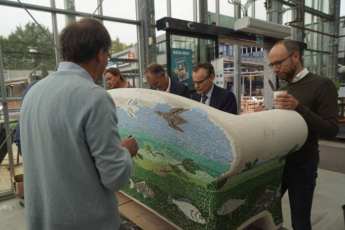 Burgemeester Röell helpt bij beplakken Social Sofa bij woonwarenhuis Nijhof