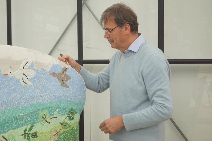 Burgemeester Röell helpt bij beplakken Social Sofa bij woonwarenhuis Nijhof