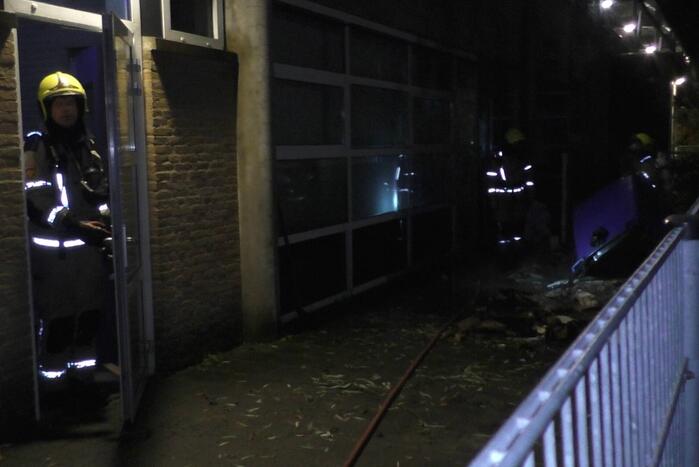 Brandweer blust brandende container tegen school