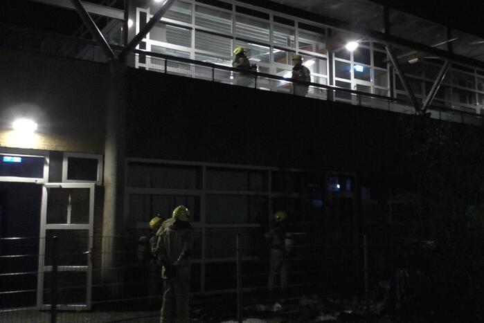 Brandweer blust brandende container tegen school