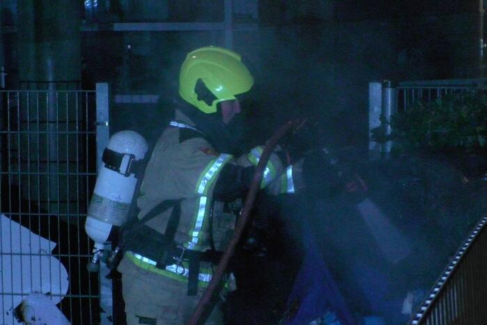 Brandweer blust brandende container tegen school