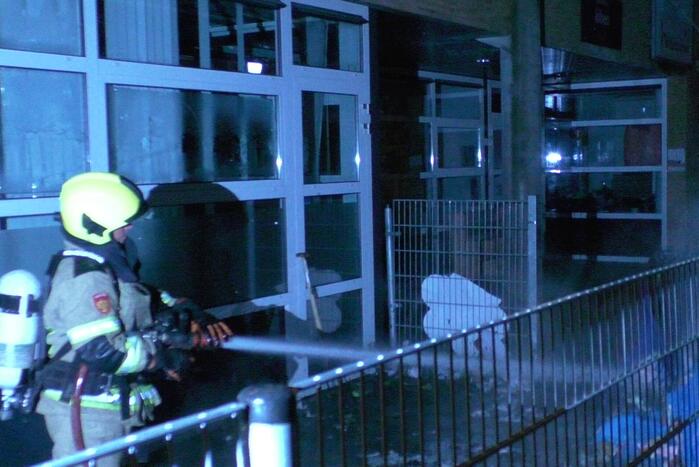 Brandweer blust brandende container tegen school