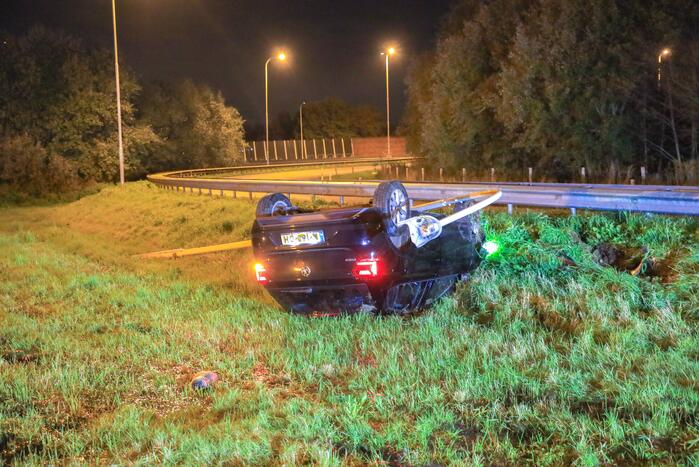 Auto belandt op z'n kop naast snelweg