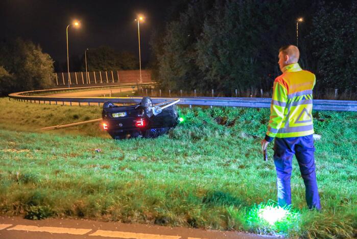 Auto belandt op z'n kop naast snelweg