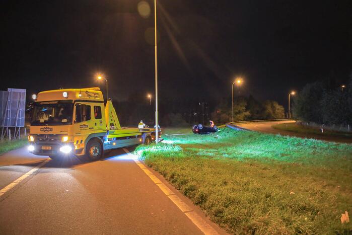 Auto belandt op z'n kop naast snelweg