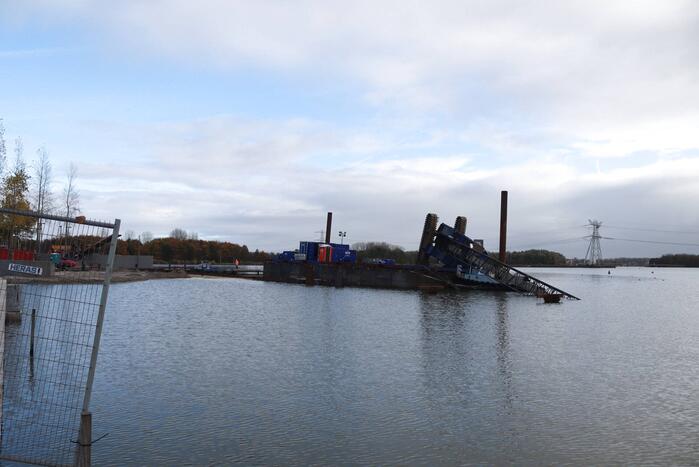 Hijskraan op ponton valt in water