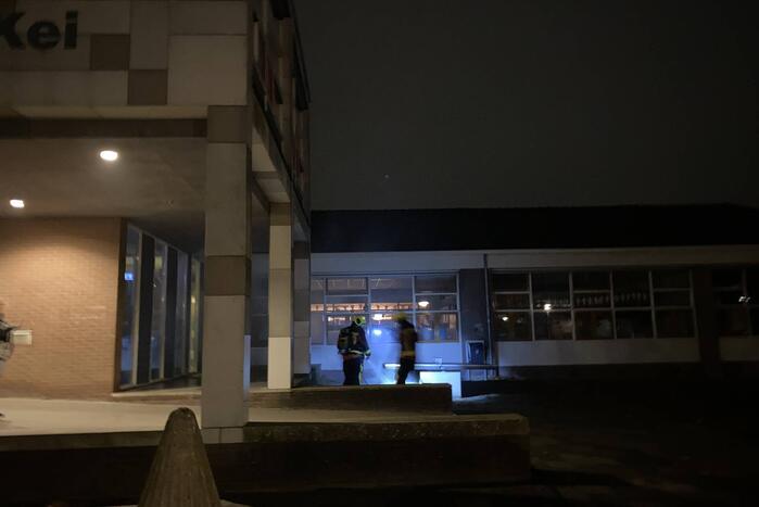 Brandweer blust brandende hoop kranten op schoolplein