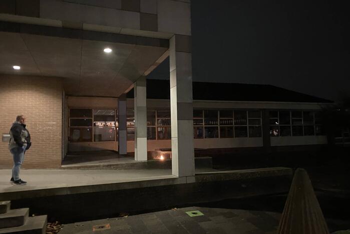 Brandweer blust brandende hoop kranten op schoolplein