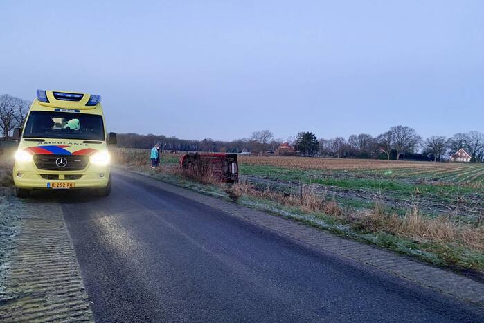 Auto belandt op zijn kant langs spekgladde weg
