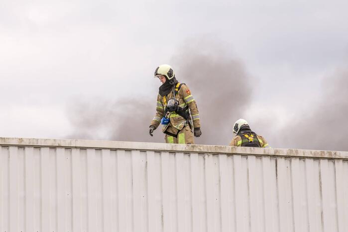 Zwarte rookpluimen bij brand op dak van sporthal