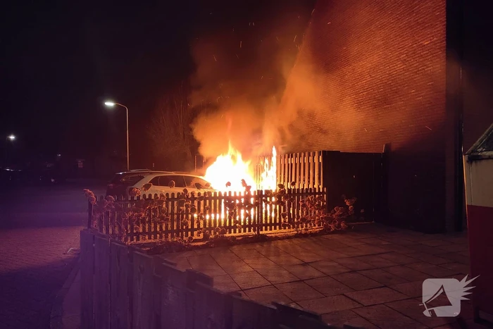 Auto en schutting in brand