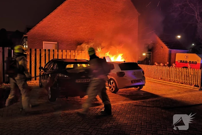 Auto en schutting in brand