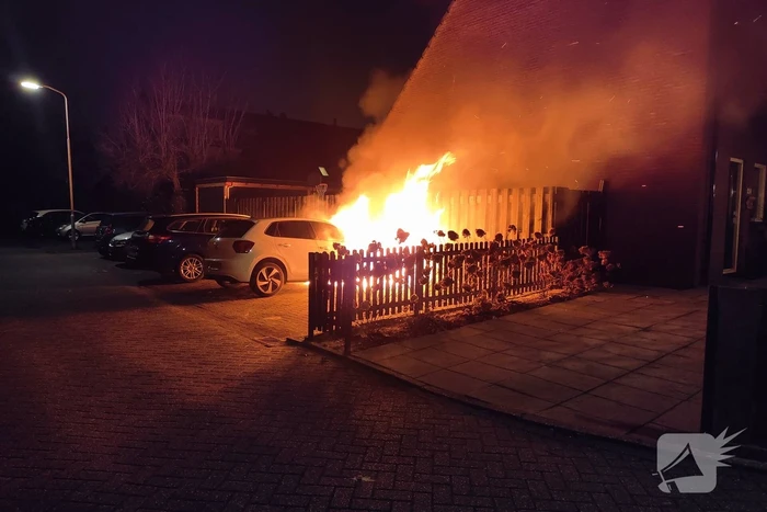 Auto en schutting in brand