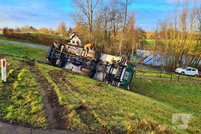 Vrachtwagen belandt op zijn kant onderaan dijk