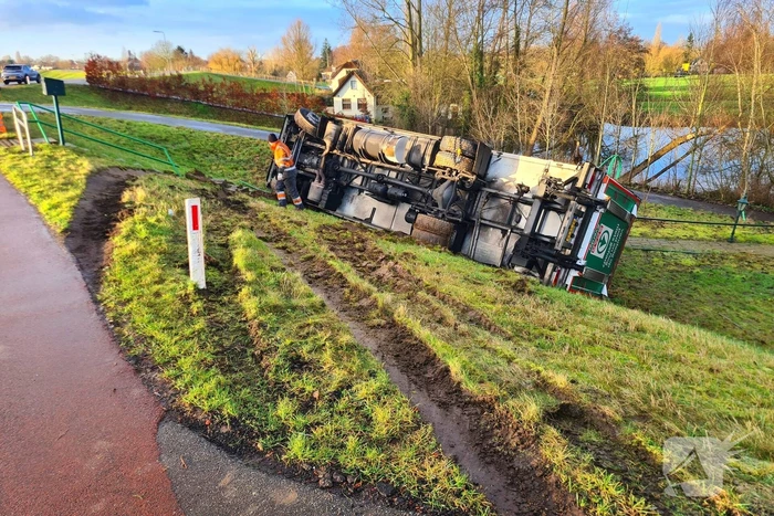 Vrachtwagen belandt op zijn kant onderaan dijk