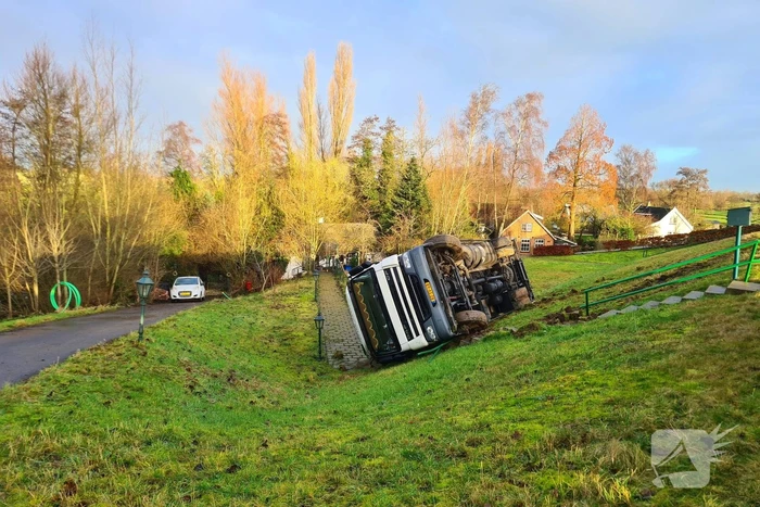 Vrachtwagen belandt op zijn kant onderaan dijk
