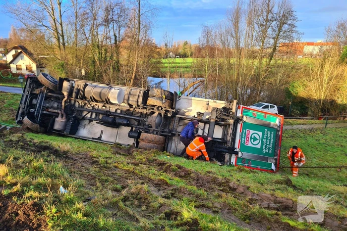 Vrachtwagen belandt op zijn kant onderaan dijk