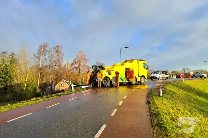 Vrachtwagen belandt op zijn kant onderaan dijk