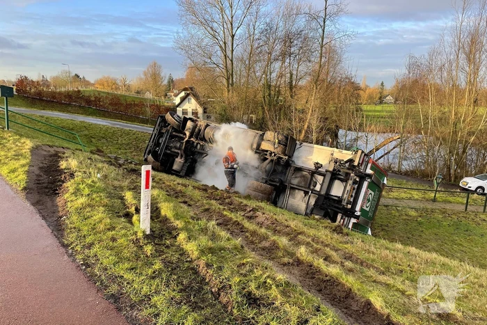 Vrachtwagen belandt op zijn kant onderaan dijk