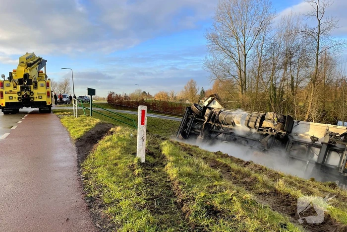 Vrachtwagen belandt op zijn kant onderaan dijk