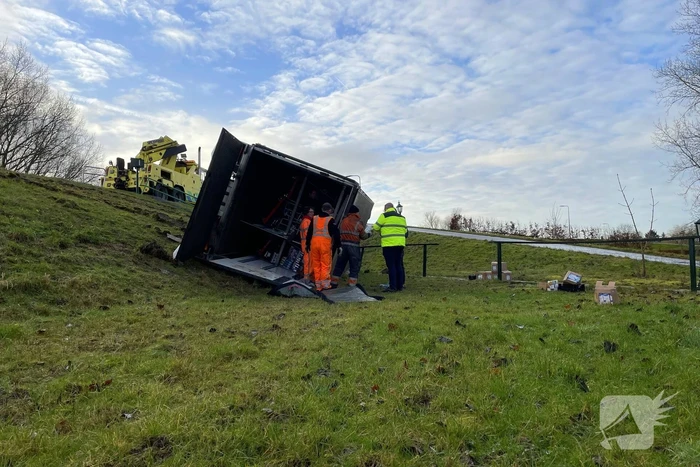 Vrachtwagen belandt op zijn kant onderaan dijk