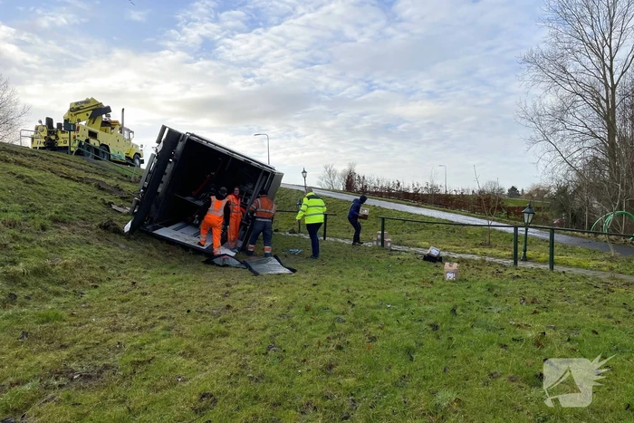 Vrachtwagen belandt op zijn kant onderaan dijk