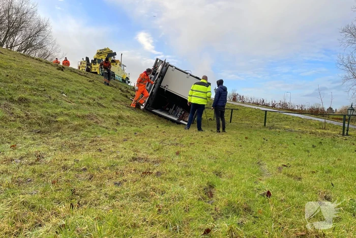 Vrachtwagen belandt op zijn kant onderaan dijk