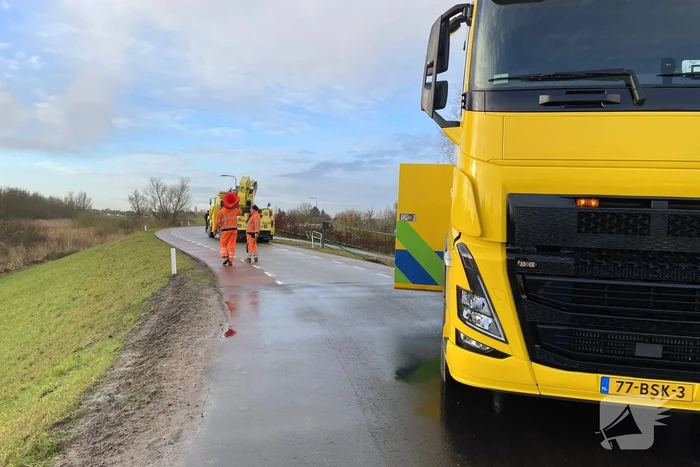 Vrachtwagen belandt op zijn kant onderaan dijk
