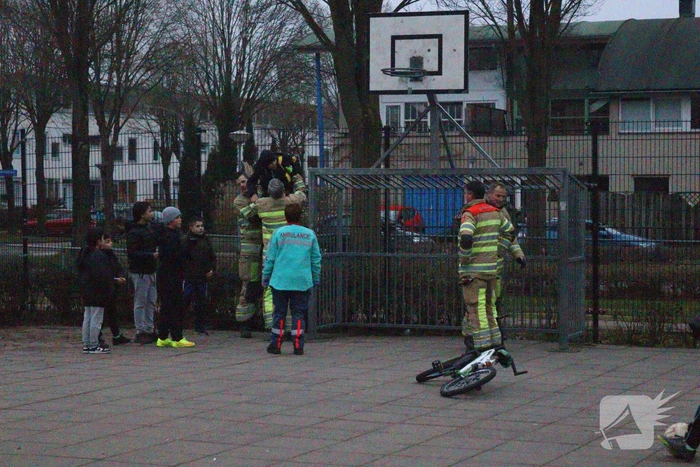 Kind vast met voet tussen spijlen voetbaldoel