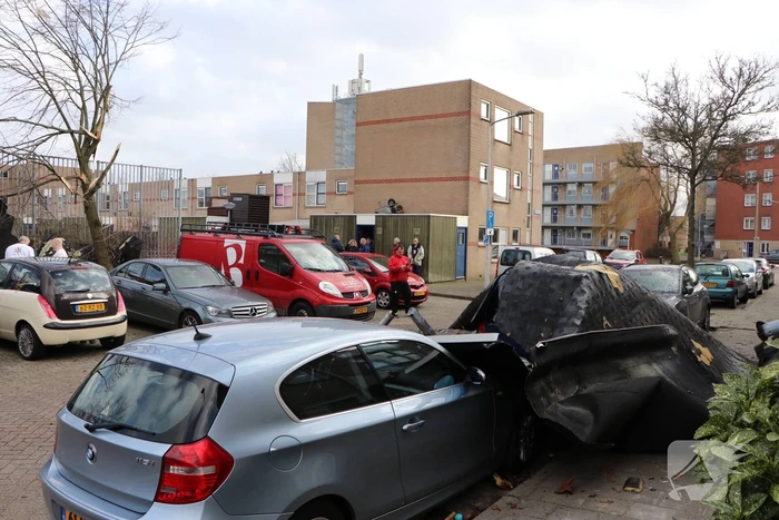 Dakbedekking van flat waait over auto's en lantaarnpalen