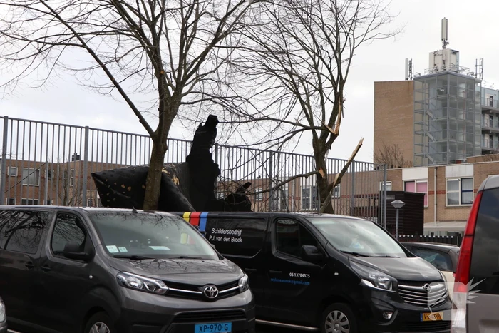 Dakbedekking van flat waait over auto's en lantaarnpalen