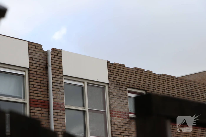 Dakbedekking van flat waait over auto's en lantaarnpalen
