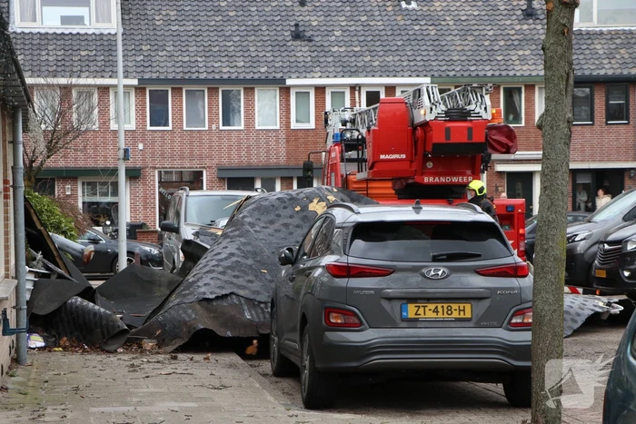Dakbedekking van flat waait over auto's en lantaarnpalen