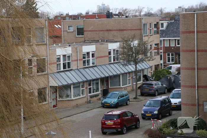Dakbedekking van flat waait over auto's en lantaarnpalen