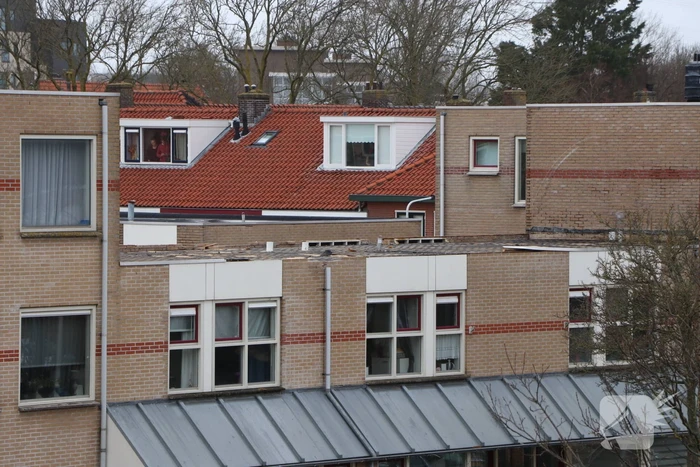 Dakbedekking van flat waait over auto's en lantaarnpalen