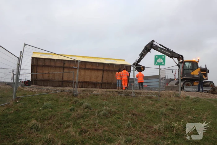 Bouwkeet waait om en belandt op wegdek