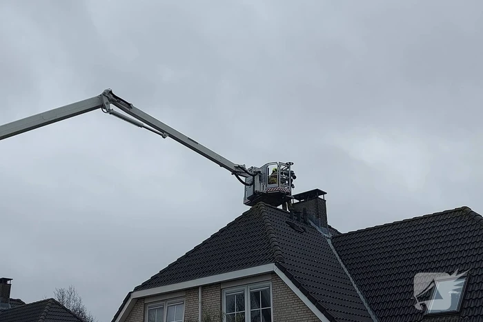 Brandweer verwijderd losse plaat op schoorsteen van woning