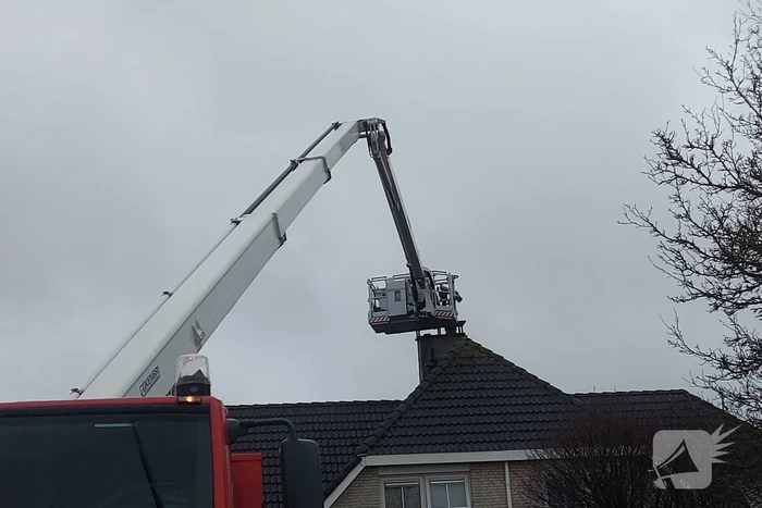 Brandweer verwijderd losse plaat op schoorsteen van woning