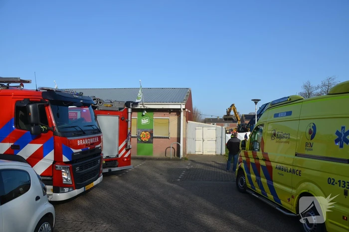 Persoon bekneld onder omgevallen graafmachine
