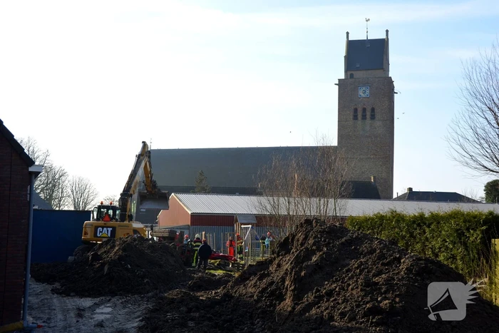 Persoon bekneld onder omgevallen graafmachine