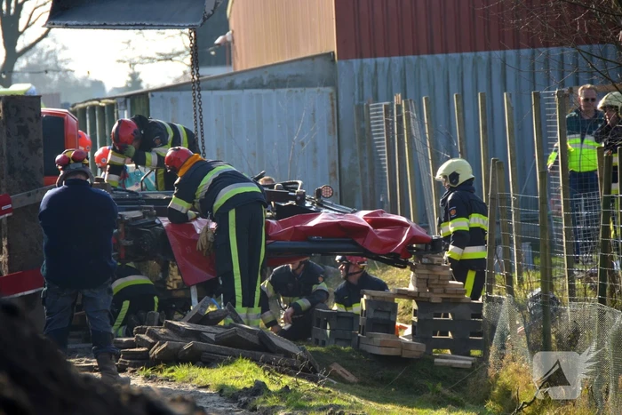 Persoon bekneld onder omgevallen graafmachine