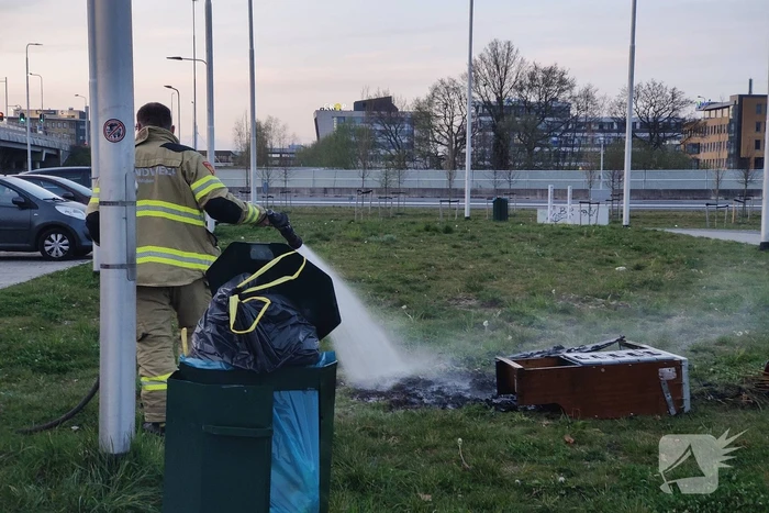 Brandweer blust brandende afvalcontainer