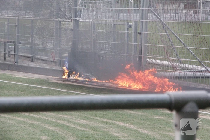 Vlammen bij brand naast sportveld