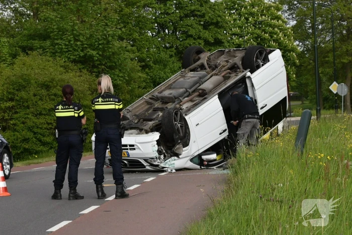Bestelbus botst tegen paal en slaat over de kop