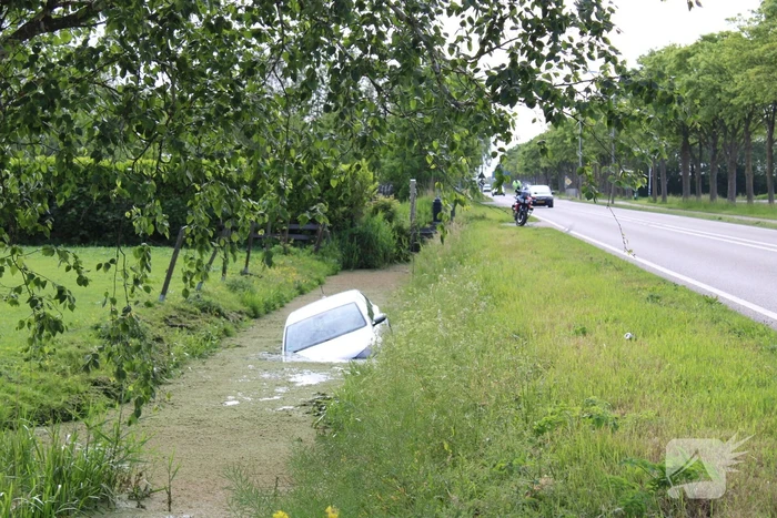 Personenauto raakt te water naast doorgaande weg
