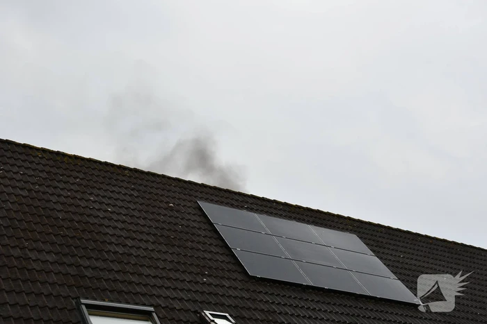 Veel rook uit zolderraam bij brand in woning