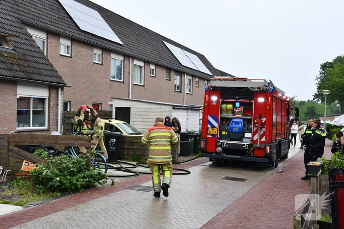 Veel rook uit zolderraam bij brand in woning