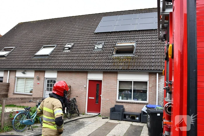 Veel rook uit zolderraam bij brand in woning