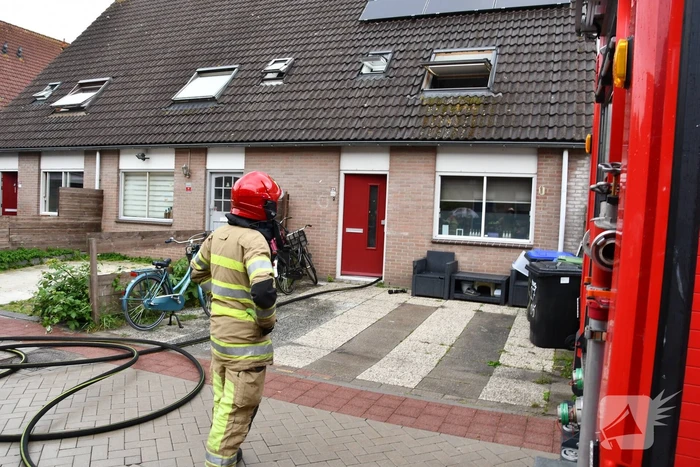 Veel rook uit zolderraam bij brand in woning