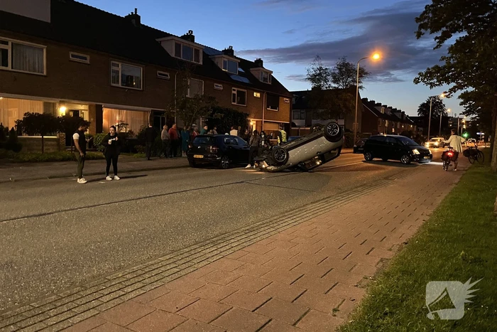 Auto op zijn kop na botsing met geparkeerde auto